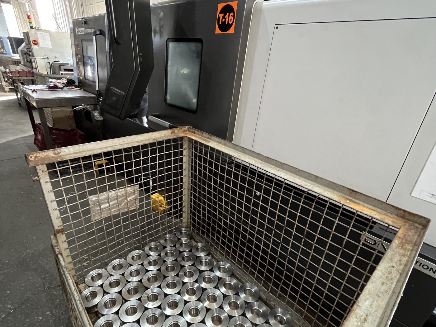 Gefertigte Drehteile im Transportbehälter neben CNC-Maschine